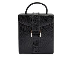 Compact fold-out jewelry box in black plant-based materials, shown closed with an upright top carry handle and a secure vertical strap closure with a silver metal bar accent.