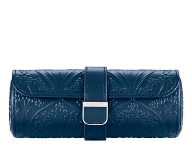 WOLF X LIBERTY All Over Ianthe Triple Watch Roll shown from a straight front view, showcasing a sleek cylindrical silhouette in deep navy blue, featuring an intricately debossed botanical art nouveau pattern and a centered leather snap-closure strap with 