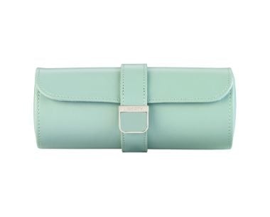 WOLF X LIBERTY Julia Interior Print Triple Watch Roll shown from a straight front view, showcasing a sleek cylindrical silhouette in soft sage green, featuring a minimalist smooth lid texture and a centered leather snap-closure strap with a polished silve