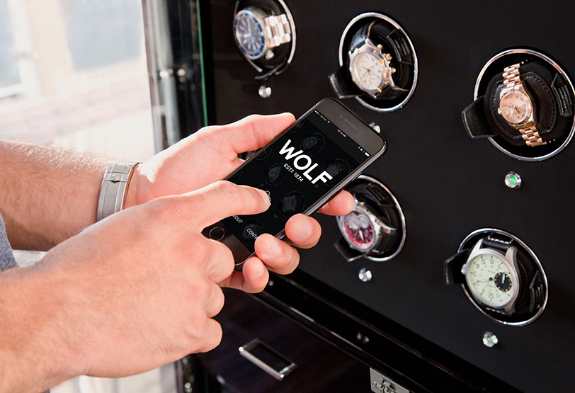 Hand using WOLF app to control a watch winder cabinet.